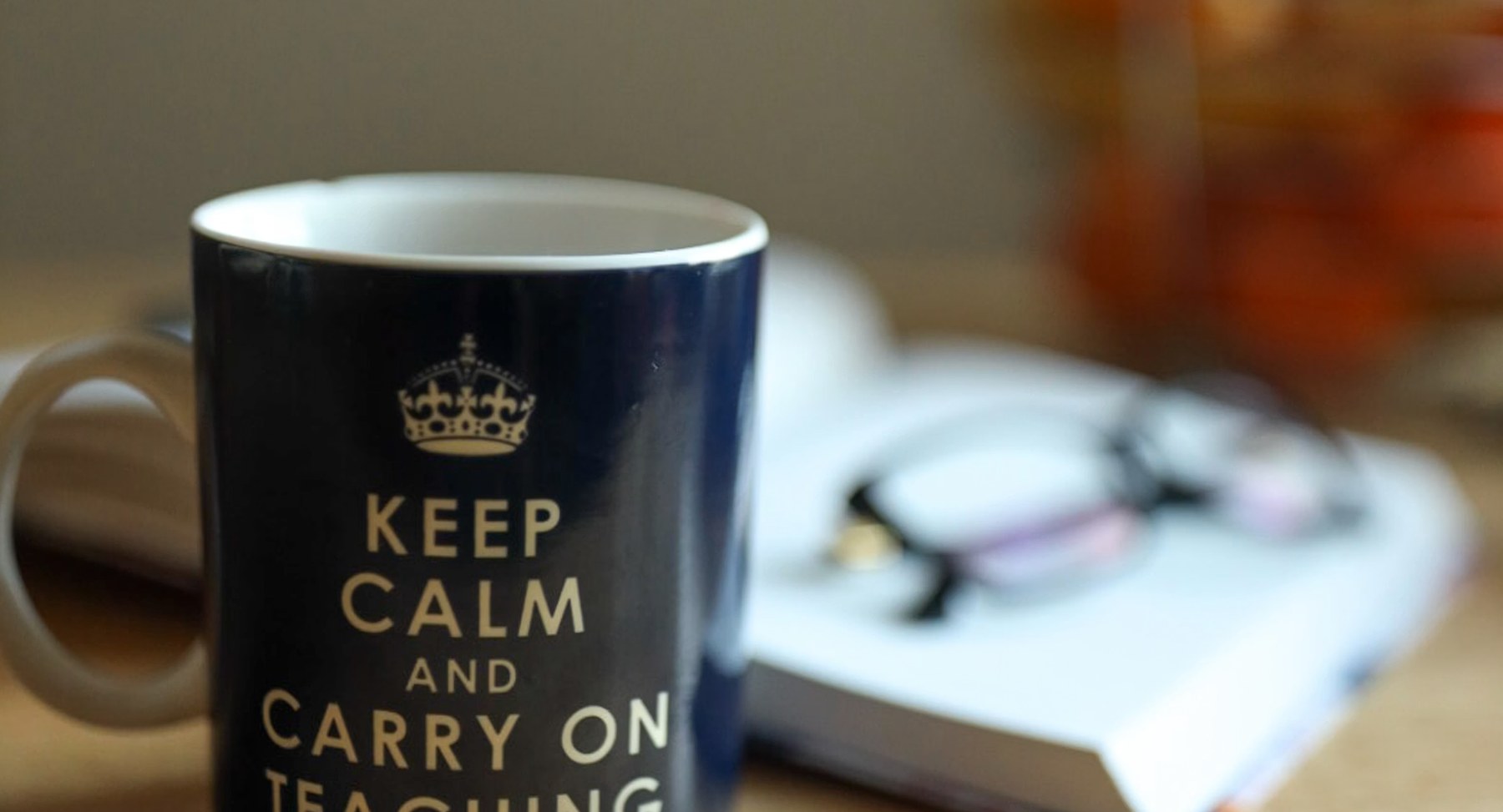 A mug, a book and a pair of glasses on a kitchen table in the evening