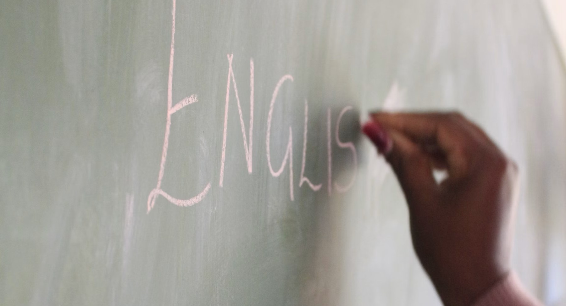 A hand writing on a chalkboard at the start of a lesson