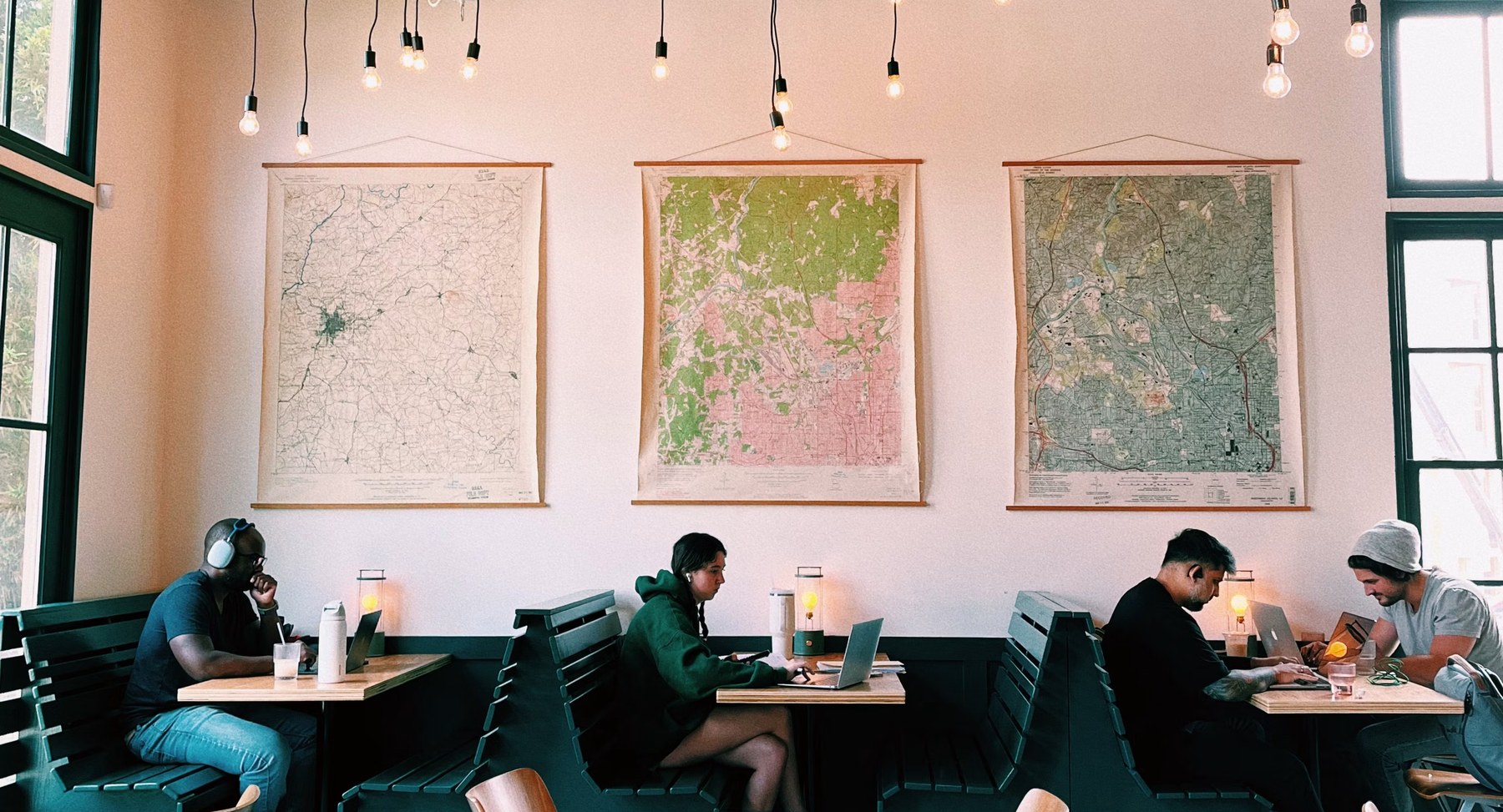 People working alone on laptops at separate tables in a café